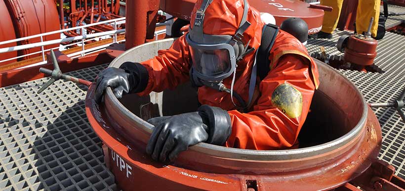 Man in chemical suit entering inside cargo tank